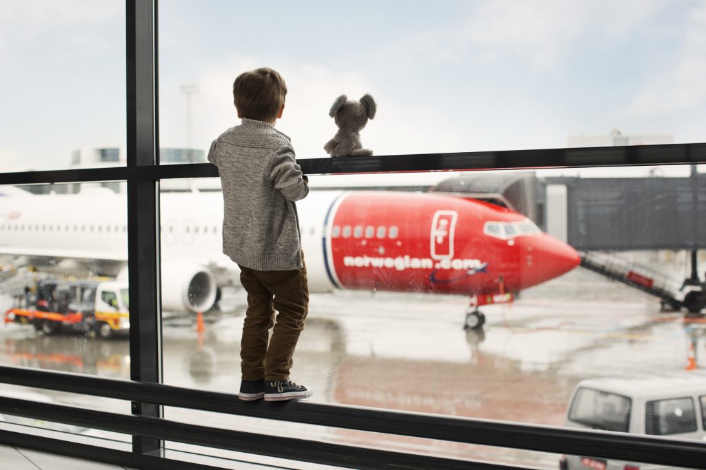 Gutt på flyplass ser på et Norwegian-fly på gaten